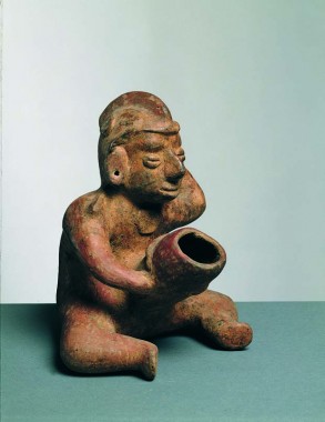 Den siddende mand, der bærer en hætteagtig hue med kam, holder på en overdimensioneret penis og har den venstre hånd ført op til nakken, højde 19,5 cm, Colima, ca. 100 f.Kr-400 e.Kr.
