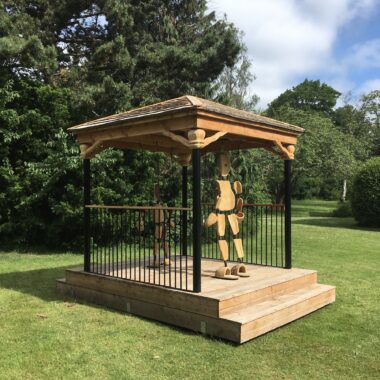 Hartmut Stockter, Marionetdukkepavillon, 2017, træ, rustfrit stål, gummi, ca. 3,2 x 2,5 m x 3,7 m. Den besøgende kan stikke hænderne i figurernes hule træhænder og fødderne i figurernes træfødder. Derved bliver det muligt at bevæge figurerne. Foto: Hartmut Stockter.